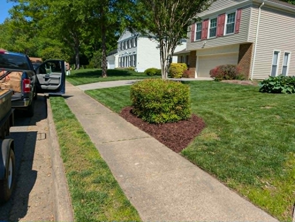 Backyard landscape bed with mulch, river rock, and stone paver edging